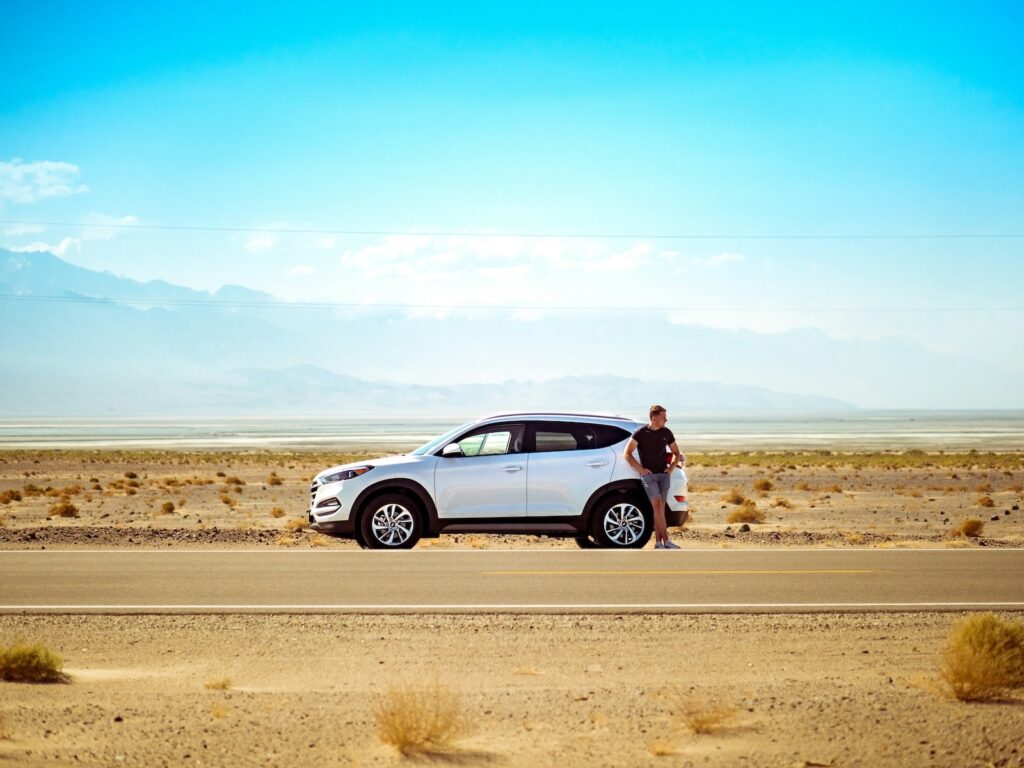 man standing next to car in the arizona desert